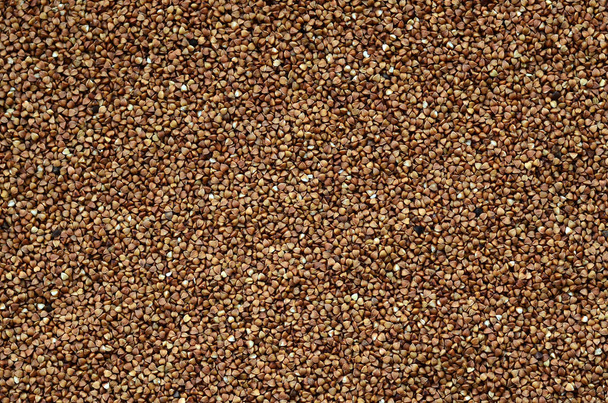 Background texture of a large pile of buckwheat. Many buckwheat grains close-up in daylight - Фото, зображення
