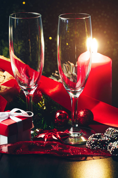 Christmas or New Year. Champagne in glasses with candles, panettone and gift with red satin bow. Copy-space. Holiday Concept - Photo, Image