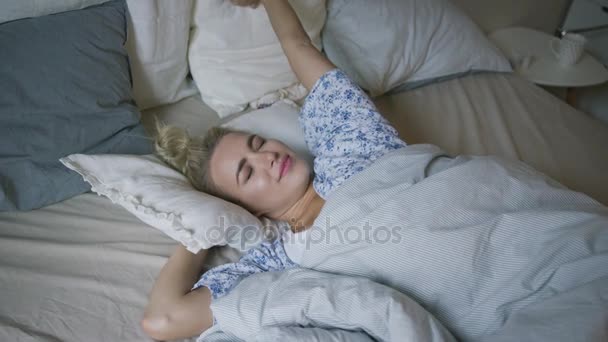 Woman stretching arms in bed - Кадри, відео