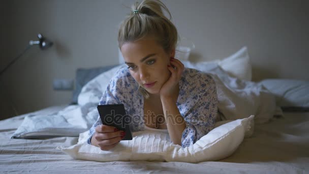 Pretty woman using smartphone in bed - Filmagem, Vídeo