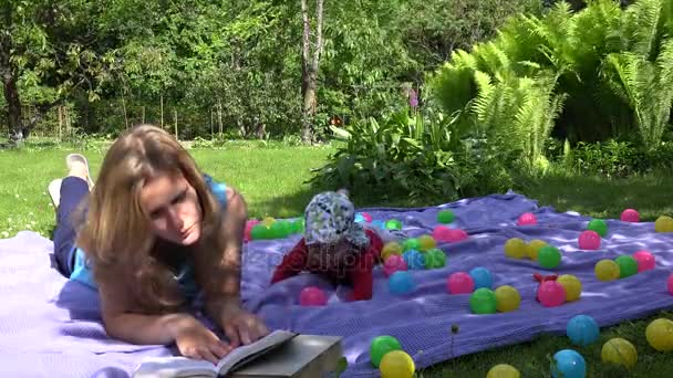 vrouw boek lezen op plaid en baby jongen jongen crawl. 4k - Video