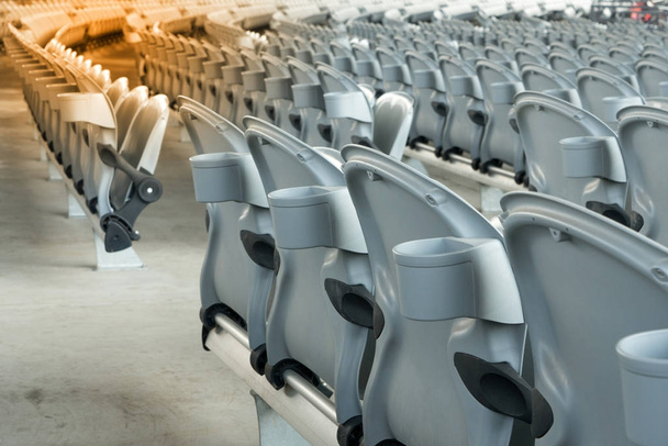 Bílá plastová skládací prázdná červená sedadla na koncertní nebo fotbalový stadion. Řada sedadel fotbalového stadionu se slunečním světlem. - Fotografie, Obrázek
