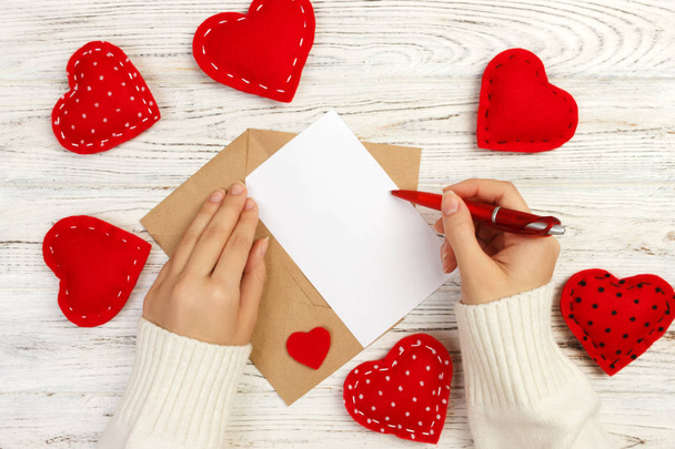Kezét a lány szerelmes levelet írt a Valentin-nap. Kézi készítésű képeslapot. Nő írási képeslapot, 14 február ünnep ünnepe. Lapos feküdt. Szemközti nézet - Fotó, kép