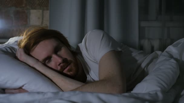 赤毛の髭の男のベッドに横たわって、夜暗い部屋で眠っています。 - 映像、動画