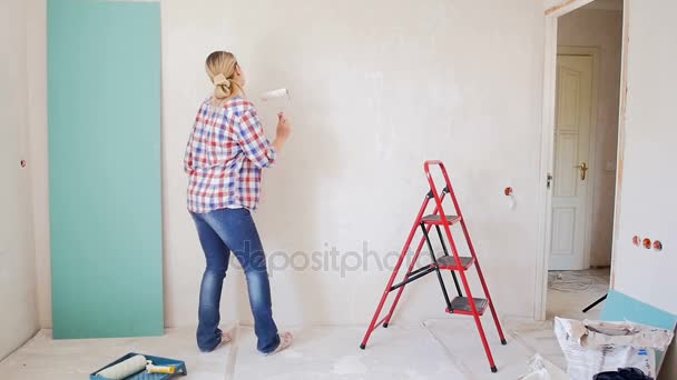Αργή κίνηση μήκος σε πόδηα του νεαρή γυναίκα χορεύει ενώ ζωγραφική τοίχου στο νέο διαμέρισμα - Πλάνα, βίντεο