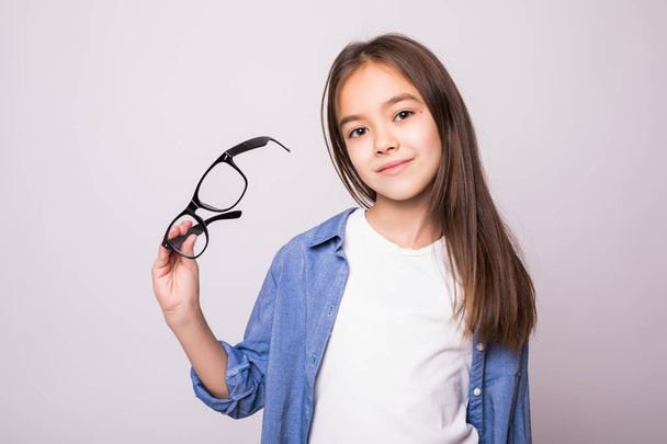 Portrait of Happy beauty little girl with glasses in hands isolated on gray background - Photo, Image