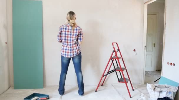Gelukkig jonge vrouw muur schilderen en dansen op Nieuw appartement - Video