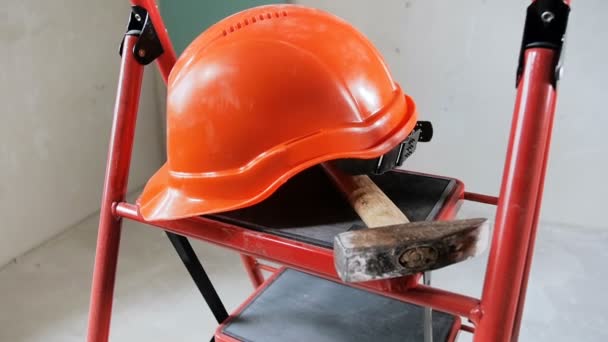 Slow motion footage of red hardhat and hammer lying on stapladder - Footage, Video