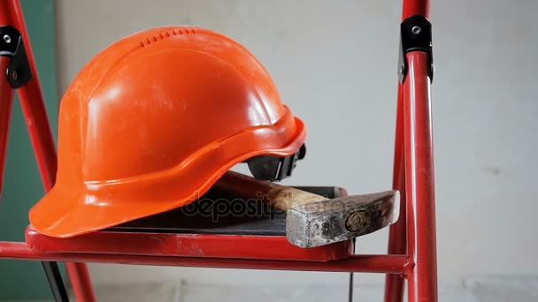 Panorámica de herramientas de trabajo y hardhat rojo acostado en escalera en la casa en proceso de renovación
 - Metraje, vídeo