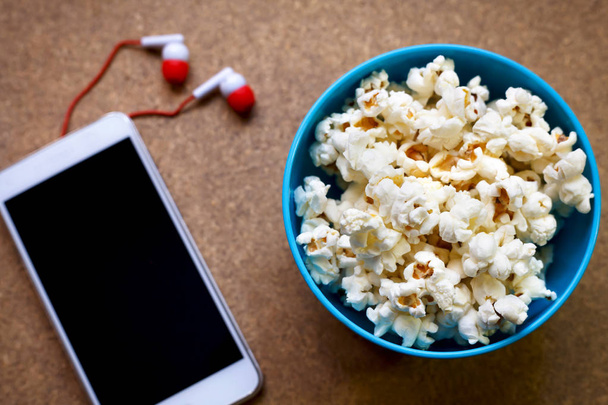 Smartphone and popcorn in bowl - Фото, изображение