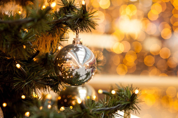 Різдвяні прикраси на зеленій ялинці. Символи новорічних куль і гірлянди на розмитому жовтому тлі, боке
 - Фото, зображення