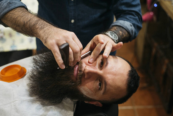 Homme barbu se faire couper les cheveux de barbe avec un rasoir par Barber
 - Photo, image
