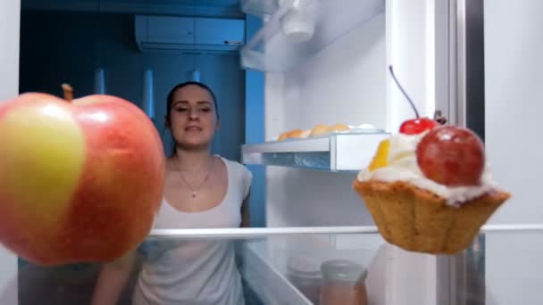 4k footage of young woman taking fresh apple from fridge at kitchen - Filmagem, Vídeo
