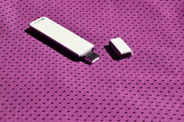 Un adaptateur wi-fi USB portable moderne est placé sur les vêtements de sport violets en fibre de nylon polyester
 - Photo, image