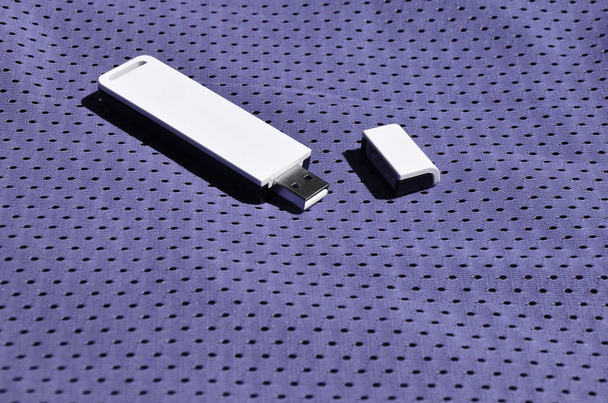 A modern portable USB wi-fi adapter is placed on the violet sportswear made of polyester nylon fiber - Foto, Imagem