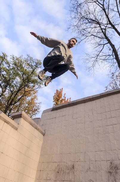 Nuori mies tekee hypyn betonikaistaleiden väliin. Urheilija harjoittelee parkour, koulutusta kadun olosuhteissa. Nuorten urheilun alakulttuurien käsite
 - Valokuva, kuva