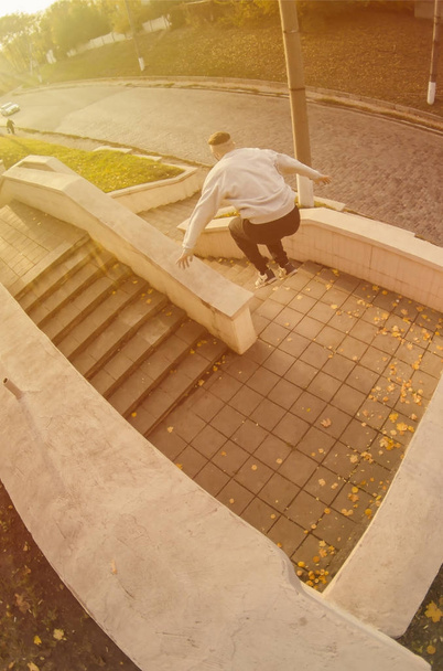 Um jovem executa um salto através do espaço entre os parapeitos de concreto. O atleta pratica parkour, treinando em condições de rua. O conceito de subculturas esportivas entre os jovens
 - Foto, Imagem