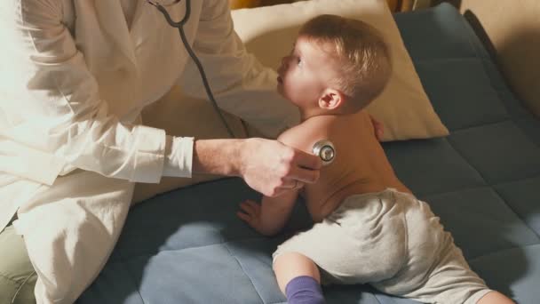 The doctor visits the baby patient at home. Baby with stethoscope - Video, Çekim