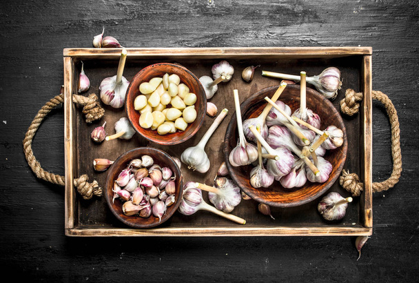 Fresh garlic in a bowl on a wooden tray. - Foto, afbeelding