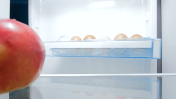 4 k záběry z sneking hlad mladá žena v lednici a kousání apple. Pojem nezdravá výživa - Záběry, video