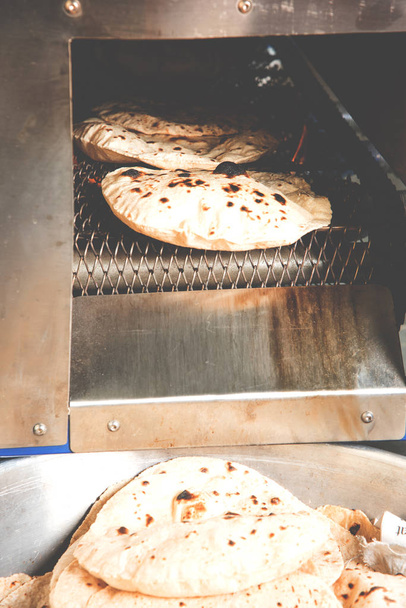 Roti or chapati making machine, selective focus. Indian ready to eat Indian flat bread coming out of machine - Φωτογραφία, εικόνα