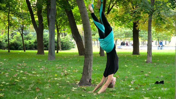 Girl in a park engaged in aerial yoga - Φωτογραφία, εικόνα