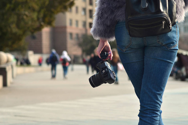 Vue arrière d'une photographe avec un appareil photo numérique moderne noir à la main sur un fond flou de rue bondée avec beaucoup de gens
 - Photo, image