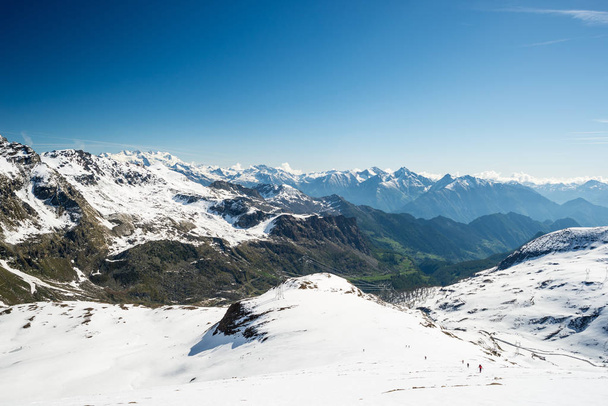 Szeroki kąt widzenia ośrodek narciarski w oddali z eleganckim szczyty wynikające z łuku alpejskim w sezonie zimowym. - Zdjęcie, obraz