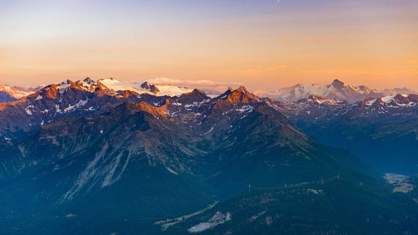 letztes sanftes Sonnenlicht über felsigen Berggipfeln, Bergrücken und Alpentälern bei Sonnenaufgang. Extreme Hochgebirgslandschaft im Aostatal, landschaftlich reizvolles Reiseziel in Italien. - Foto, Bild
