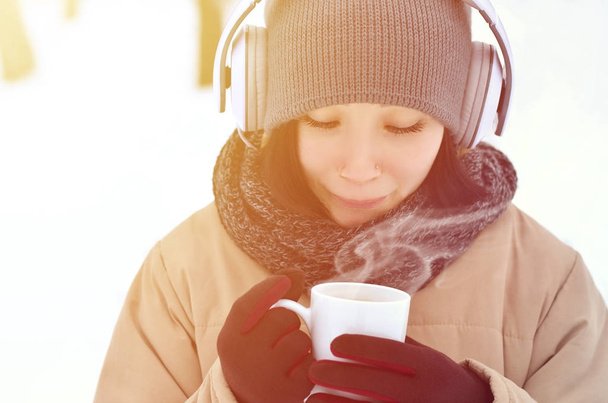 Talvi muotokuva melko houkutteleva valkoihoinen lävistetty tyttö luminen puu. Hän kuuntelee musiikkia isoilla valkoisilla kuulokkeilla kahvikuppi kädessään. Kävelee ulkoilmassa.
 - Valokuva, kuva