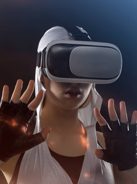 A girl in silver clothes with a hood looks into virtual reality  - Foto, Imagem