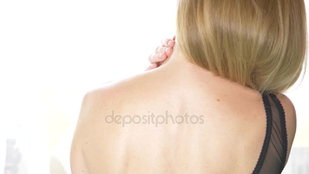 back view, close-up, 4k, slow-motion. a blonde woman takes off a bra strap with one shoulder. - Footage, Video