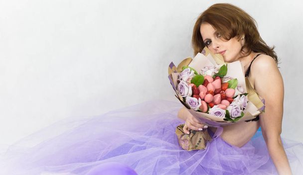 Beautiful woman in purple skirt holding bouquet from flowers, strawberry and sweets. - Zdjęcie, obraz