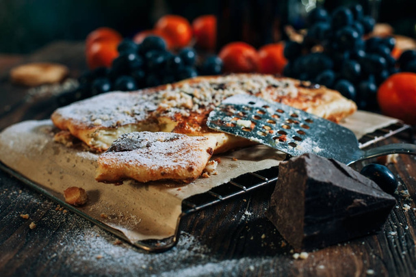 pastel de queso con chocolate, galletas, mandarinas, uvas en una mesa de madera
 - Foto, imagen