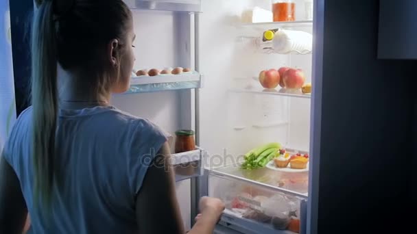 Mujer joven tomando celerfy en lugar de pastel del refrigerador. Perfecto para una nutrición saludable o video de dieta
 - Metraje, vídeo