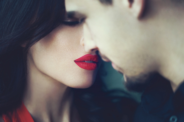 Mujer con labios rojos cerrando los ojos antes de besar a un joven
 - Foto, Imagen