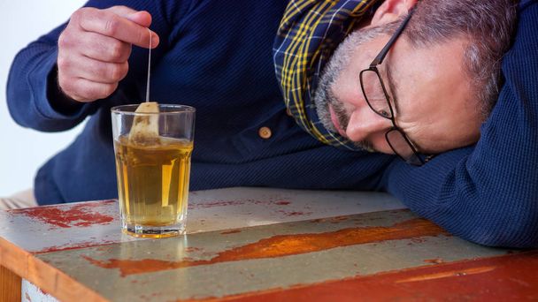 exhausted man sitting at table with glass of tea - Photo, image