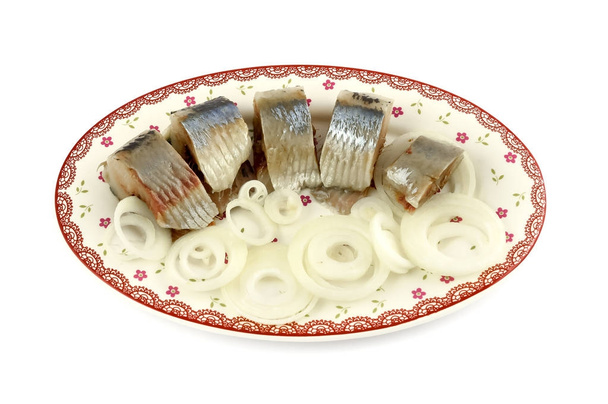 Salted herring pieces with onion rings on the plate, isolated on white background. - Фото, изображение