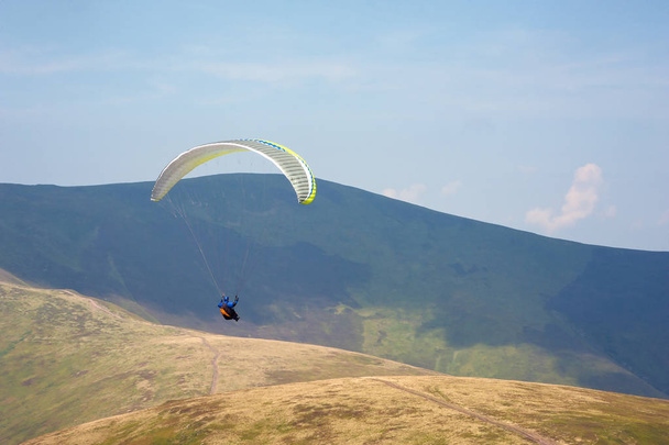El parapente vuela sobre un valle montañoso en un soleado día de verano
. - Foto, imagen