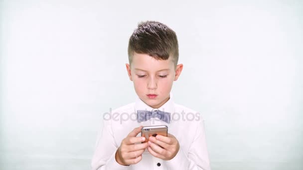 Niño muestra los pulgares hacia arriba y jugar con una tableta o teléfono inteligente sobre fondo blanco
 - Metraje, vídeo