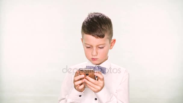 Niño muestra los pulgares hacia abajo y jugar con una tableta o teléfono inteligente sobre fondo blanco
 - Metraje, vídeo