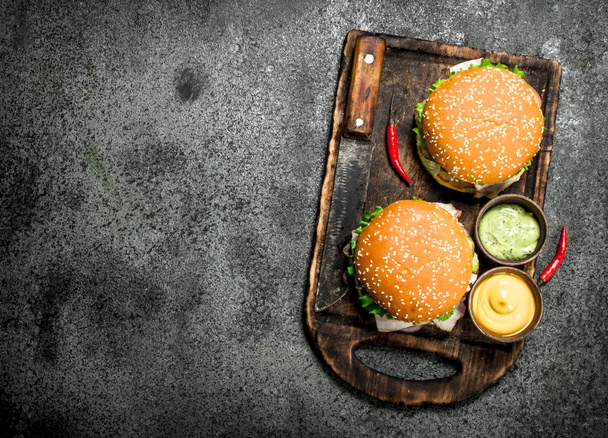 Burger mit frischem Rindfleisch und einem Messer auf dem Brett. - Foto, Bild