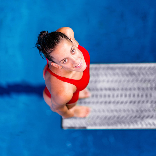 Mergulhadora em pé na prancha de salto. Preparando-se para saltar para a piscina
 - Foto, Imagem