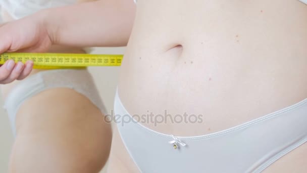 4k imagens de jovem mulher em lingerie medindo cintura com fita amarela
 - Filmagem, Vídeo