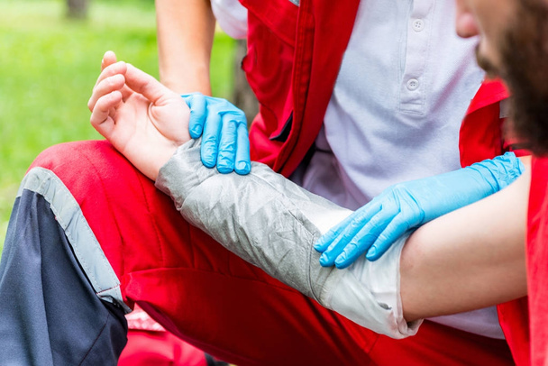 Medical worker treating burns on male's hand. First aid treatment outdoors. First aid practice - Φωτογραφία, εικόνα