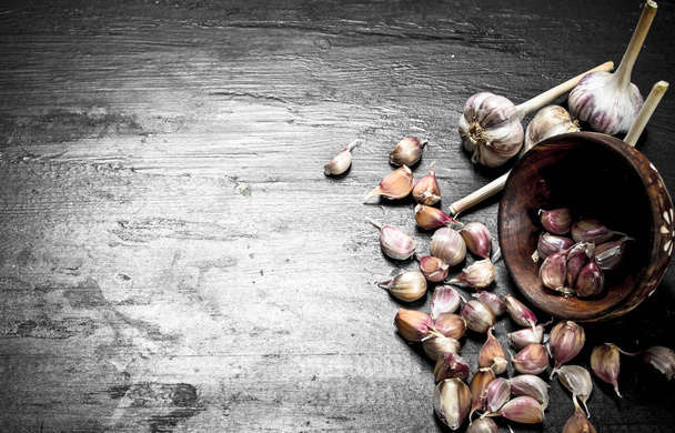 Pieces of fresh garlic in a wooden bowl. - Foto, afbeelding