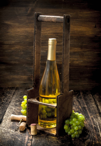 Винный фон. Белое вино на подставке с ветвями свежего винограда
. - Фото, изображение