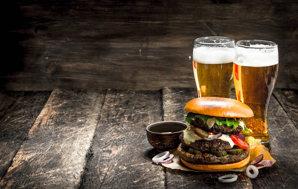 屋台の食べ物。軽めのビールのグラスと大きなハンバーガー. - 写真・画像