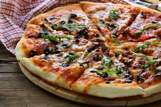 Italian pizza with mushrooms and olives on a wooden board - Photo, Image