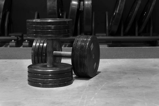 Dos pesas de metal negro viejas y usadas. Equipo de entrenamiento y fitness. Imagen en blanco y negro, foto
. - Foto, imagen